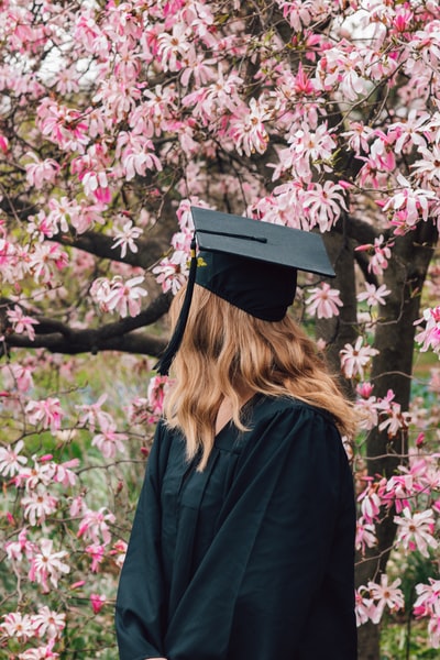 女人黑色学位服站在紫色的花
